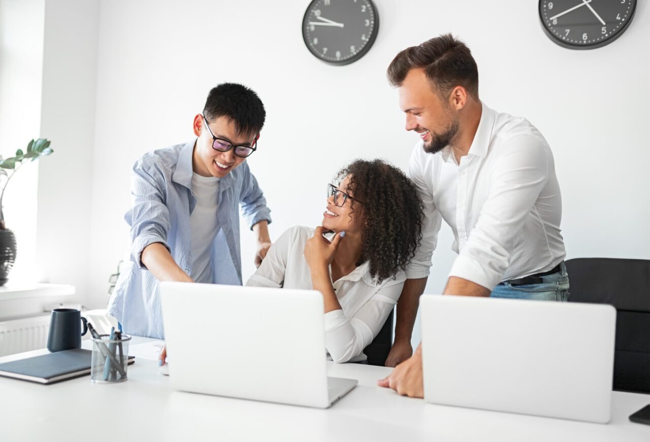Positive colleagues working with laptop in office