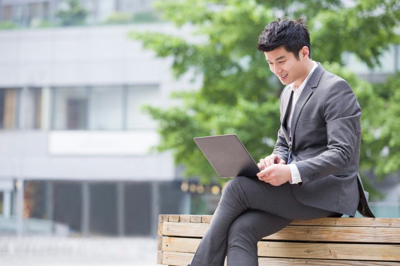 Young businessman working with laptop outdoors