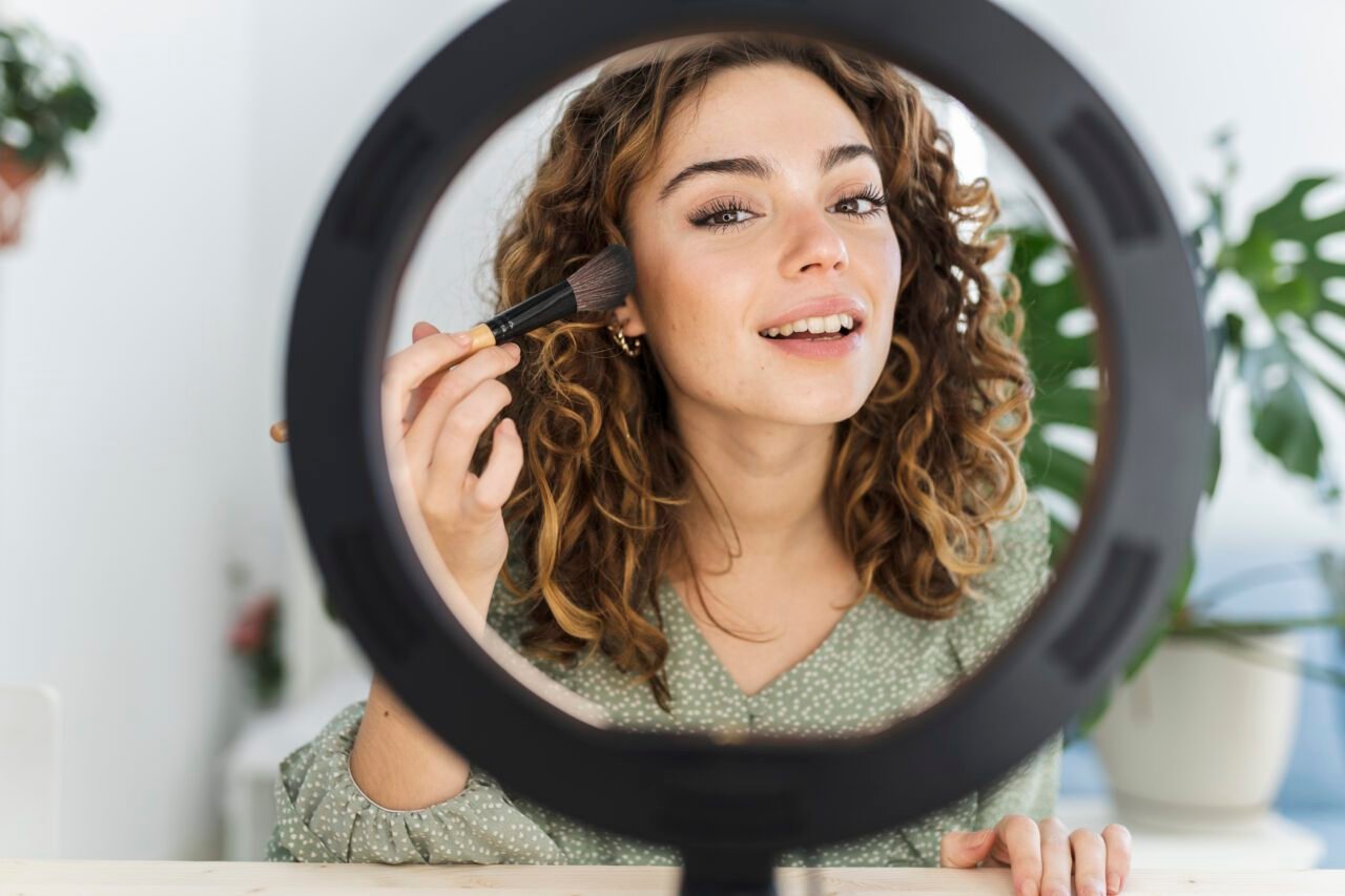 pretty woman putting on makeup at home with light
