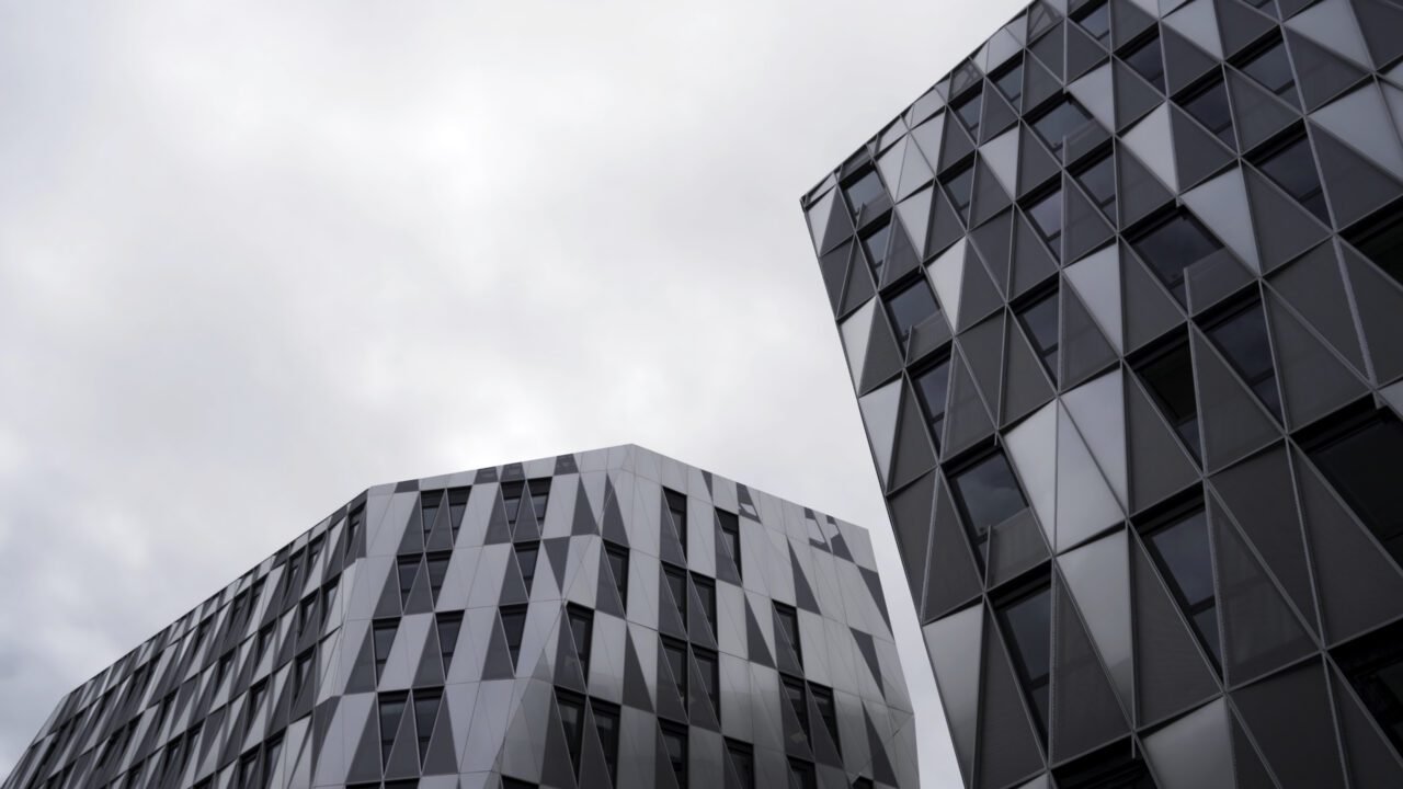 bottom-view-of-modern-unique-building-with-triangle-shaped-windows-of-black-color-on-bright-cloudy-e1695971005517.jpg