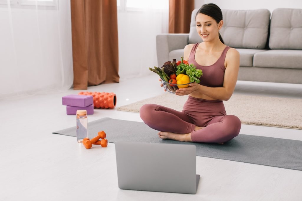 Athletic young woman blogger nutritionist holds vegetables and leads video call on proper nutrition