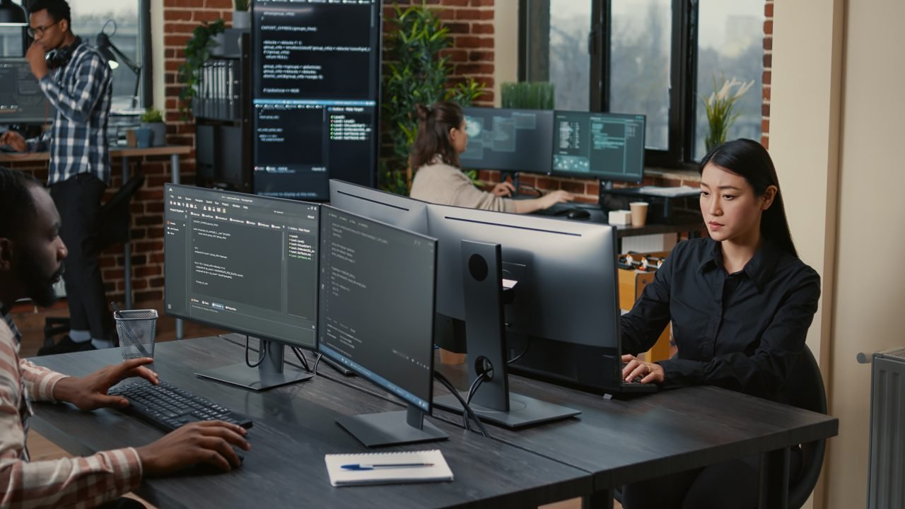 Two focused coders facing each other writing code in software development office
