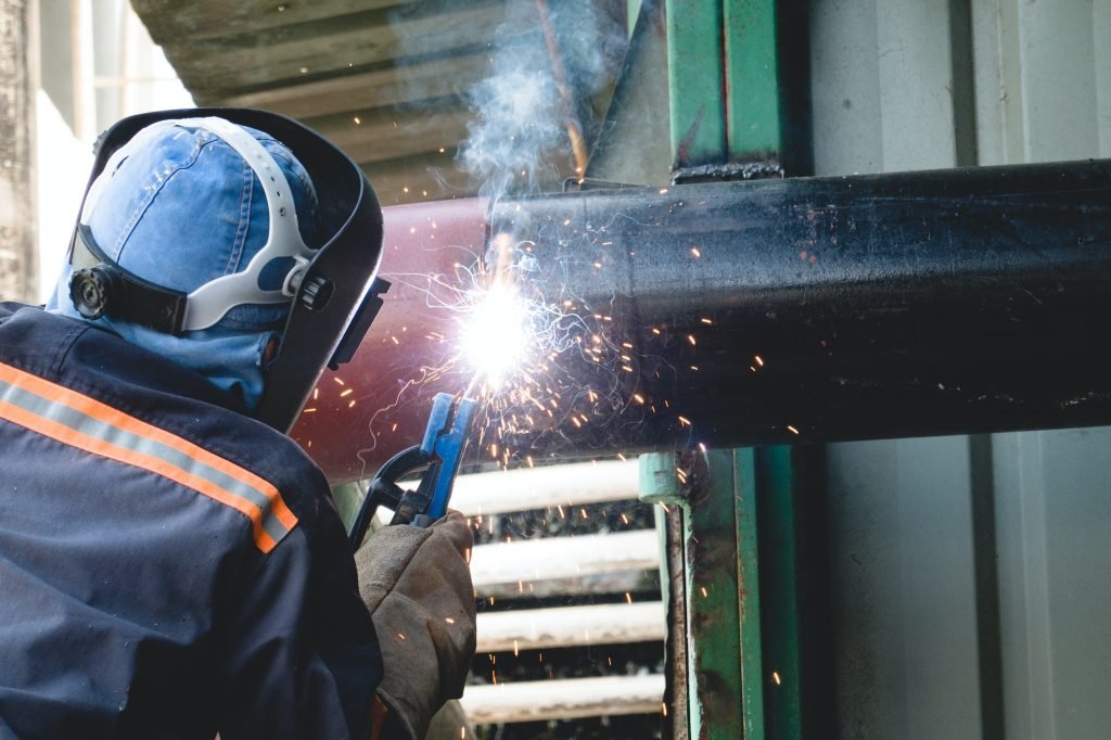 A welder is welding a water pipe system in an industrial plant.
