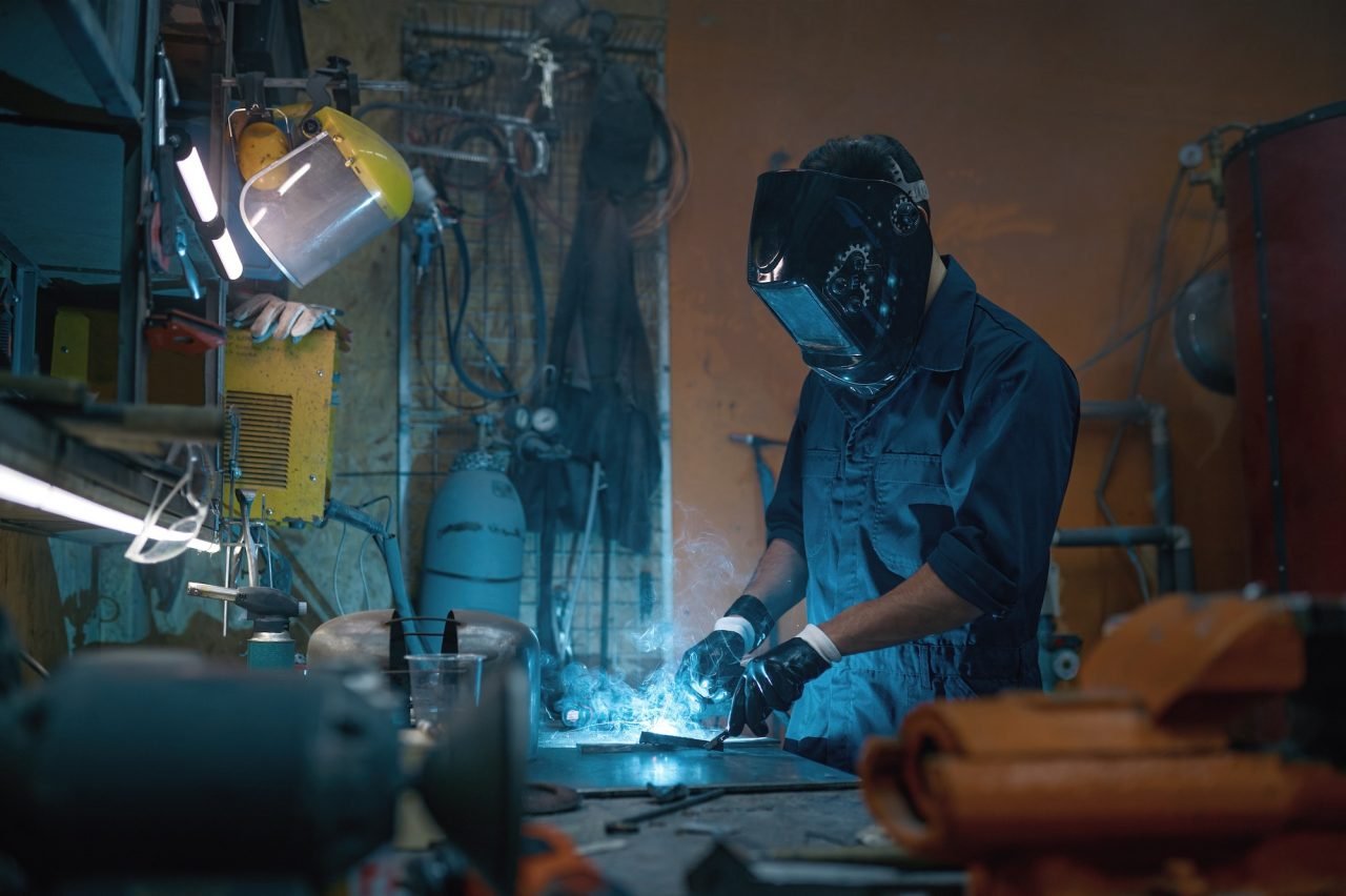 Repairman wearing protective helmet working with welding at motorcycle workshop