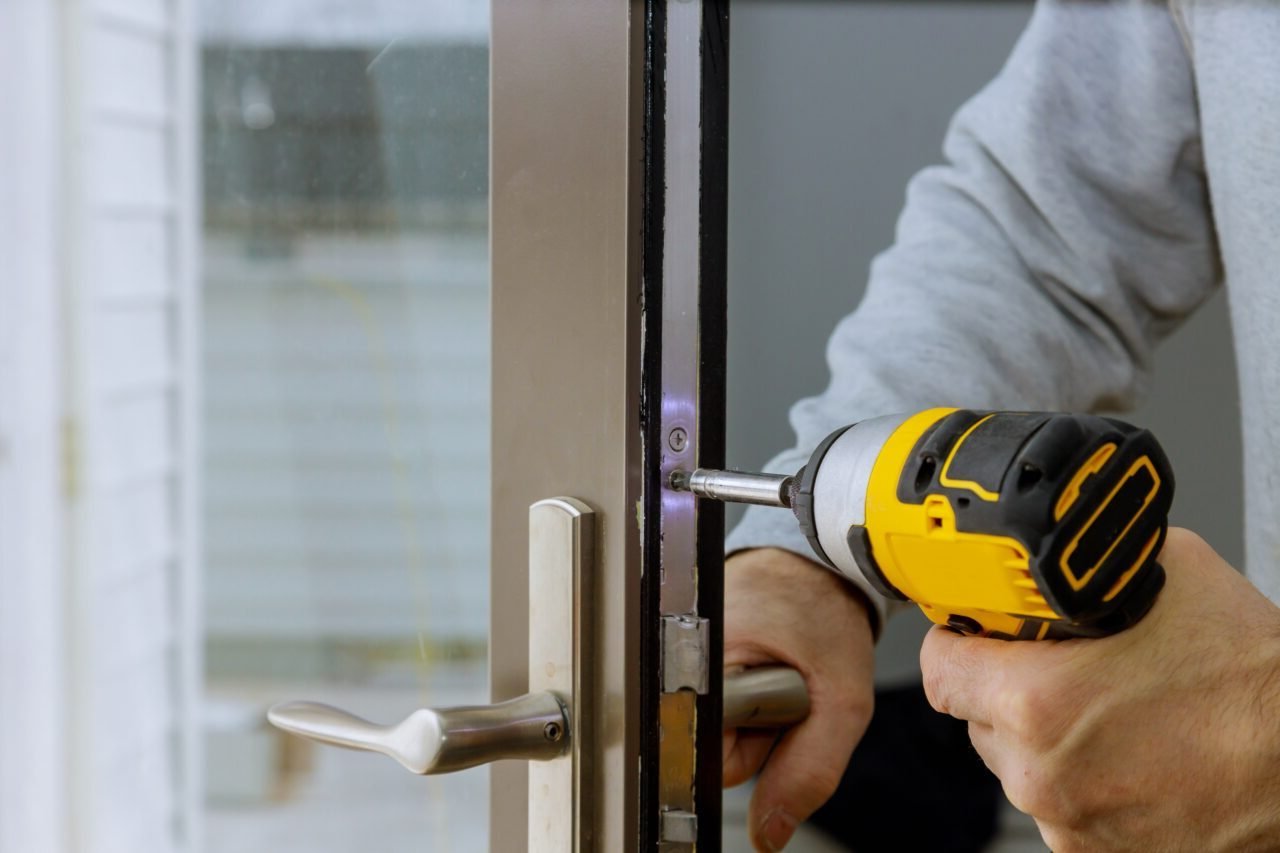 Locksmith in installing new house door lock hand holds the screwdriver