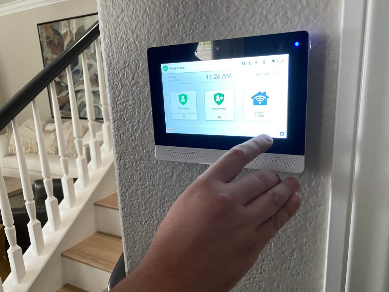 A man is setting an alarm on a smart home panel in his home