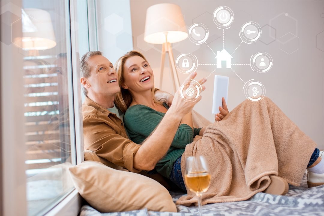 smiling wife holding digital tablet while sitting on floor with husband, smart home concept